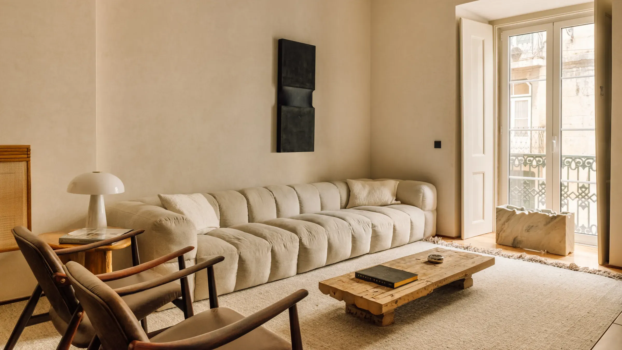 Salón de una reforma integral e interiorismo de Stylo 10: sofá modular, mesa baja de madera maciza y balcón de forja